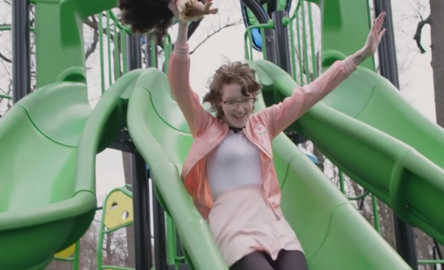 Frau rutscht auf einem Spielplatz eine Rutsche hinab.