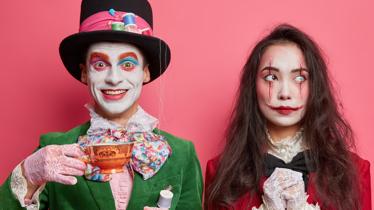 Ein Mann und eine Frau in Halloween-Kostümen vor einem pinken Hintergrund.