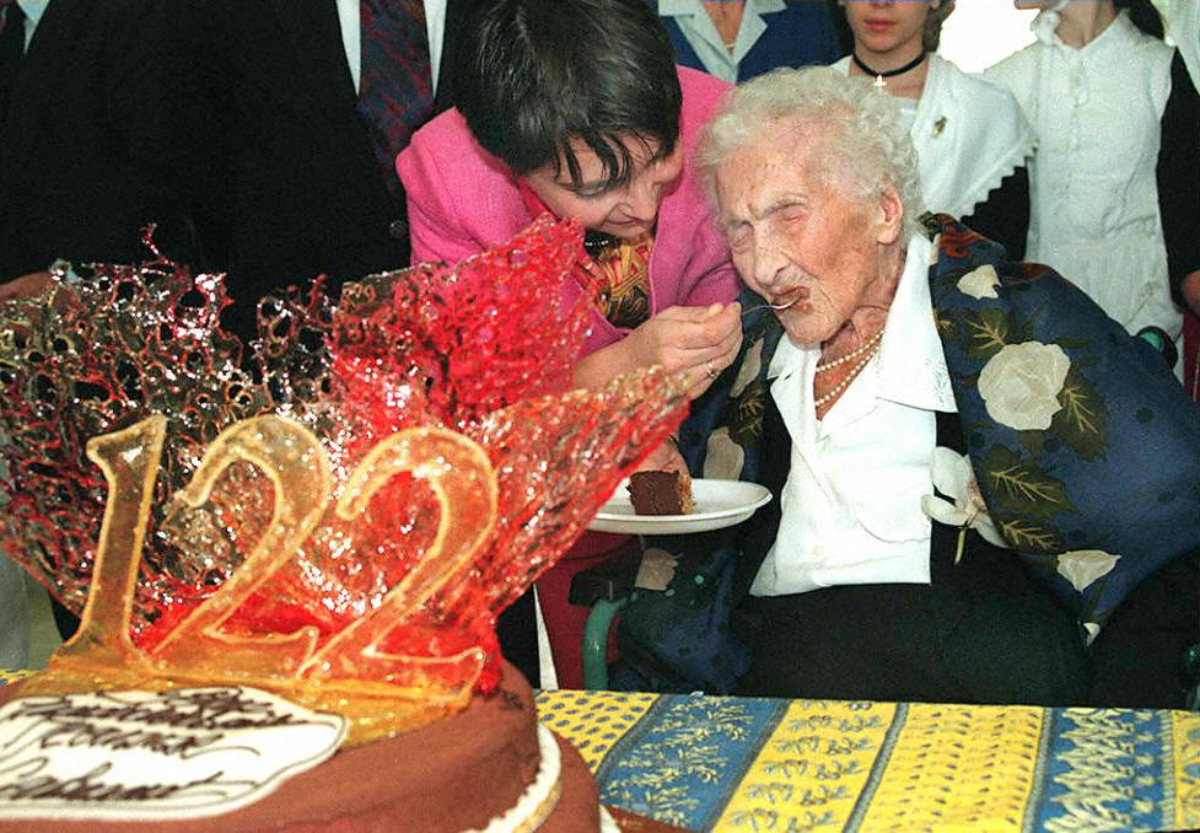 Eine alte Frau feiert ihren 122. Geburtstag und wird mit Torte gefüttert.