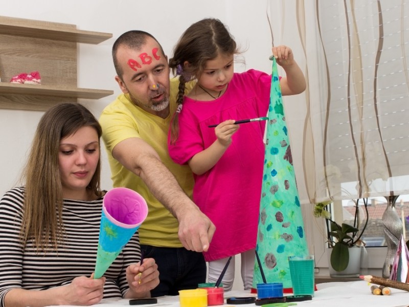 Mutter und Vater haben Spaß beim Bemalen von Schultüten