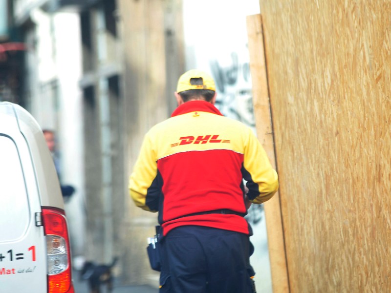 Ein Paketbote der DHL stellt eine Sendung zu.