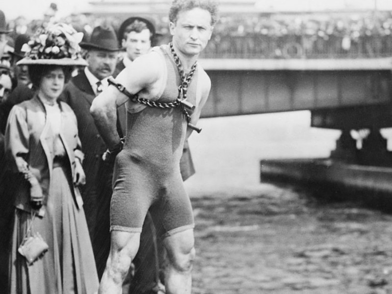 Ein Schwarzweiß-Foto vom gefesselten Harry Houdini vor seinem Sprung in den Charles River, 1904.