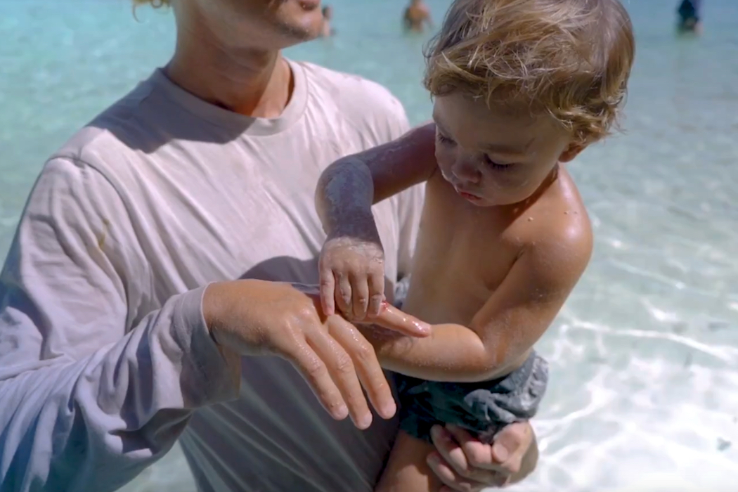 Ein Vater trägt seinen Sohn auf dem Arm. Der Sohn befühlt die Hand des Vaters.