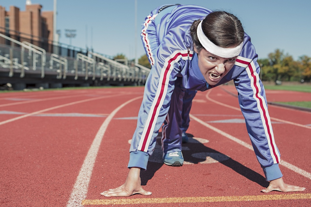 Eine Frau in Sportkleidung geht bei einem Wettlauf im Stadion in Startposition.