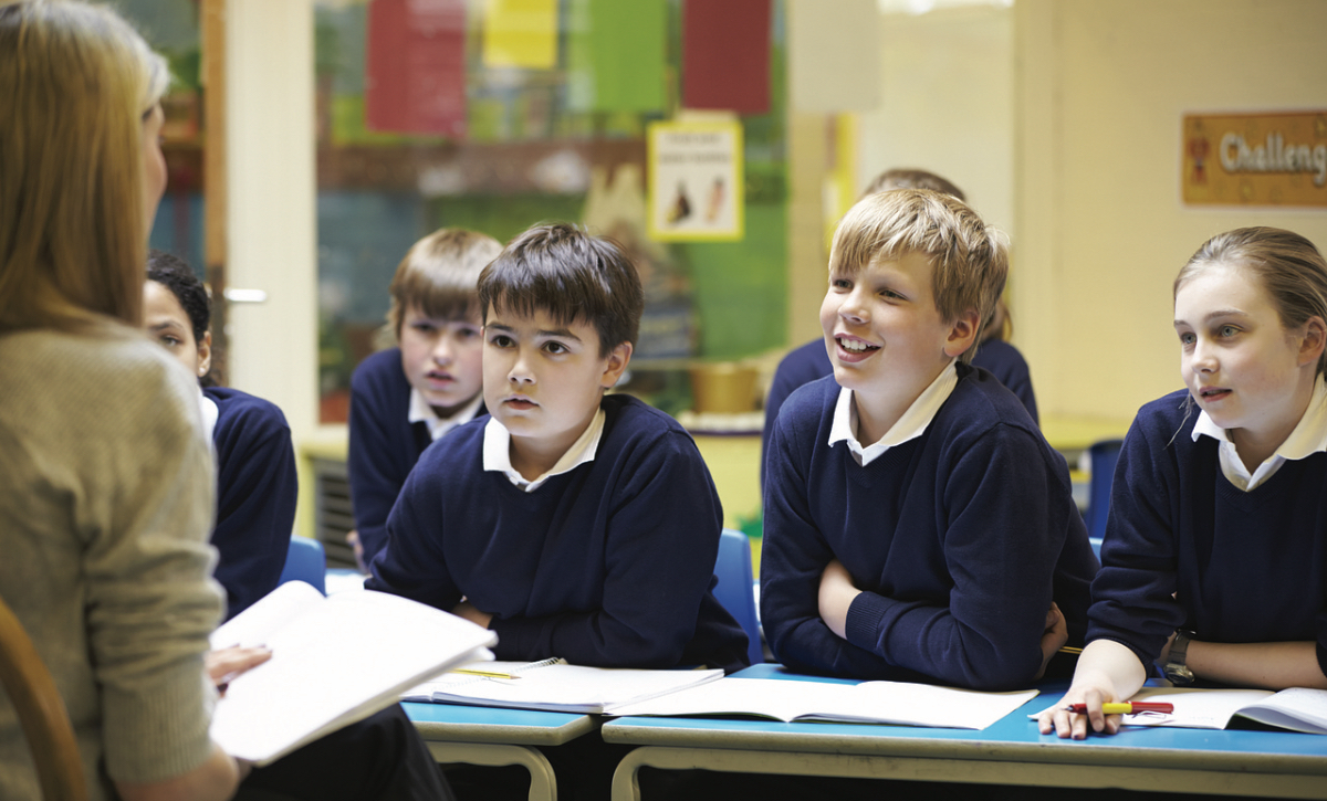 Schüler sitzen im Unterricht vor ihrer Lehrerin.