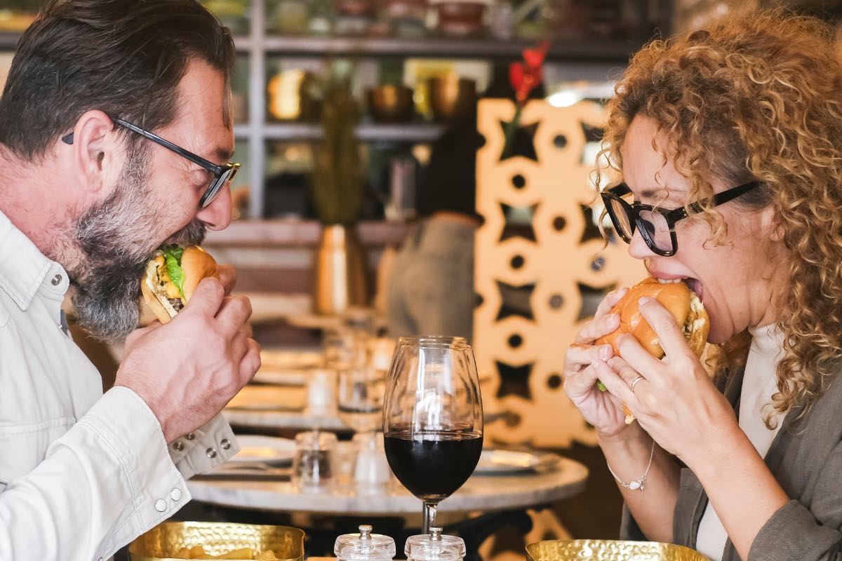 Ein glückliches Paar ist Hamburger in einem Restaurant.