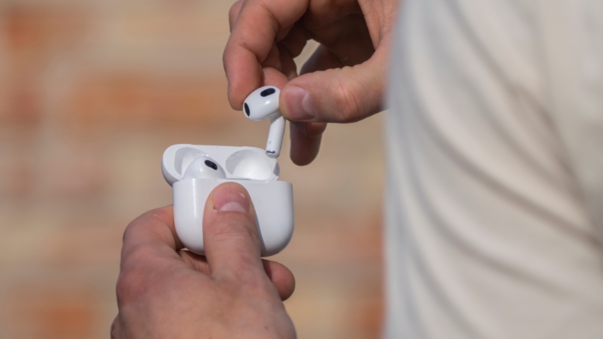 Ein Mann hält AirPods-Kopfhörer in seiner Hand.