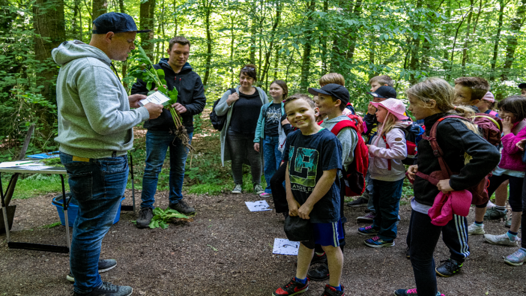 Eine Schulklasse im Wald, ein Schüler lacht in die Kamera.